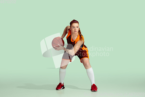 Image of Young caucasian female basketball player against mint colored studio background