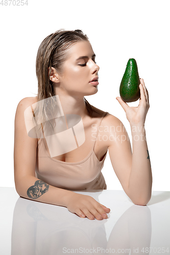 Image of Pure. Beautiful young woman with fresh avocado over white background. Cosmetics and makeup, natural and eco treatment, skin care.
