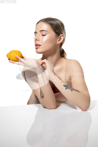 Image of Balanced. Beautiful young woman with orange over white background. Cosmetics and makeup, natural and eco treatment, skin care.