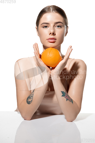 Image of Youth secrets. Beautiful young woman with orange over white background. Cosmetics and makeup, natural and eco treatment, skin care.