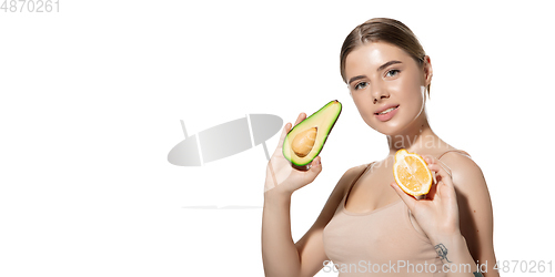 Image of Vitamins. Beautiful young woman with fresh avocado and orange pieces over white background. Cosmetics and makeup, natural and eco treatment, skin care. Flyer with copyspace.