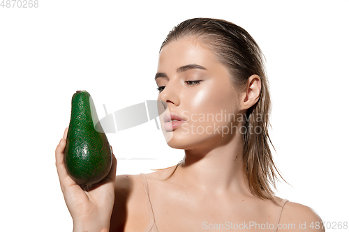 Image of Shining. Beautiful young woman with fresh avocado over white background. Cosmetics and makeup, natural and eco treatment, skin care.