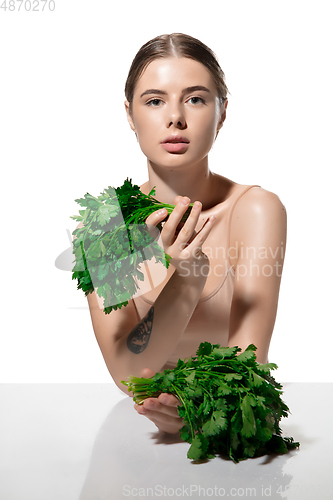 Image of Healthy. Beautiful young woman with green leaves on her face over white background. Cosmetics and makeup, natural and eco treatment, skin care