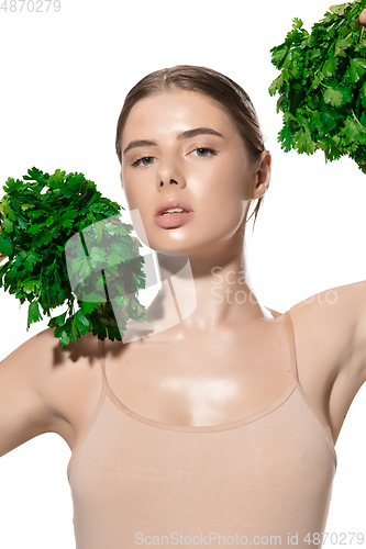 Image of Vitamins. Close up of beautiful young woman with green leaves on her face over white background. Cosmetics and makeup, natural and eco treatment, skin care