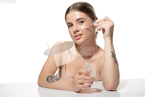 Image of Skin nutrition. Beautiful young woman with essential oil pouring over white background. Cosmetics and makeup, natural and eco treatment, skin care.