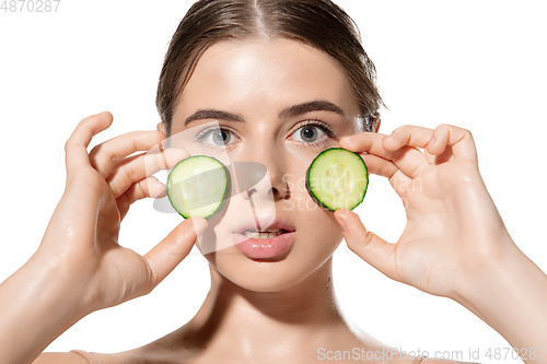 Image of Freshness. Beautiful young woman with fresh cucumber on her face over white background. Cosmetics and makeup, natural and eco treatment, skin care.