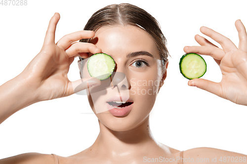 Image of Freshness. Beautiful young woman with fresh cucumber on her face over white background. Cosmetics and makeup, natural and eco treatment, skin care.