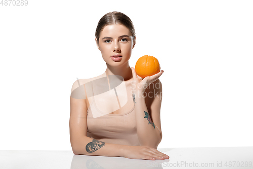 Image of Youth secrets. Beautiful young woman with orange over white background. Cosmetics and makeup, natural and eco treatment, skin care.