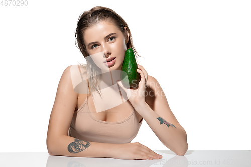 Image of Healthy. Beautiful young woman with fresh avocado over white background. Cosmetics and makeup, natural and eco treatment, skin care.