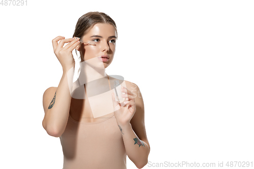 Image of Skin nutrition. Beautiful young woman with essential oil pouring over white background. Cosmetics and makeup, natural and eco treatment, skin care.