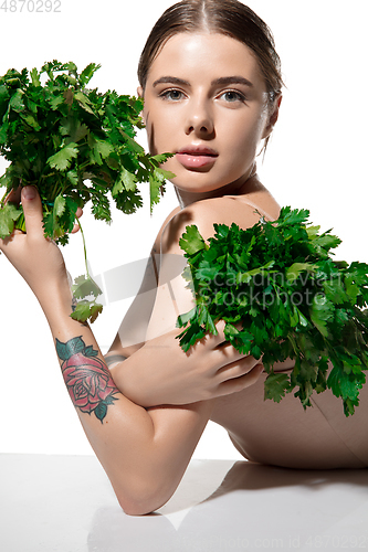 Image of Healthy. Beautiful young woman with green leaves on her face over white background. Cosmetics and makeup, natural and eco treatment, skin care