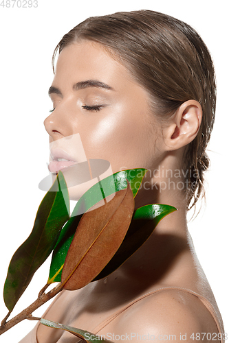 Image of Tender. Beautiful young woman with green leaves on her face over white background. Cosmetics and makeup, natural and eco treatment, skin care
