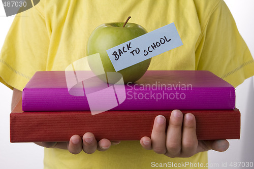 Image of detail of a kid hands with books, going back to school