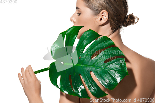 Image of Back view of beautiful young woman with green leaf on her face over white background. Cosmetics and makeup, natural and eco treatment, skin care