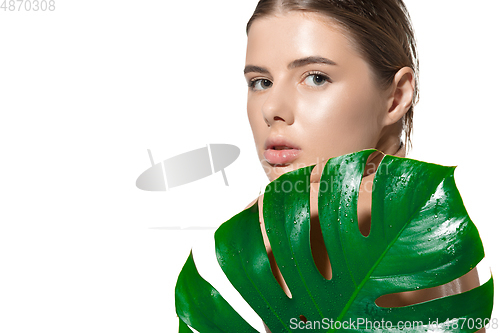 Image of Secretly. Close up of beautiful young woman with green leaves on her face over white background. Cosmetics and makeup, natural and eco treatment, skin care