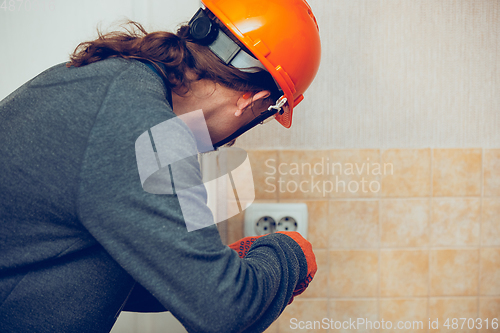 Image of Electrician repair a wall socket. Closeup of man repairing an electrical outlet. Hazardous concept, high voltage, risk, wiring replacement, technician\'s occupation