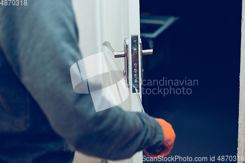 Image of Close up of handyman repair the door lock in the room, fixing lock with screwdriver in the home or office