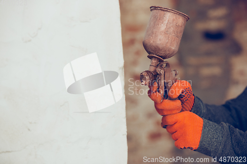 Image of Close up of hands of repairman, professional builder working indoors, coloring the wall