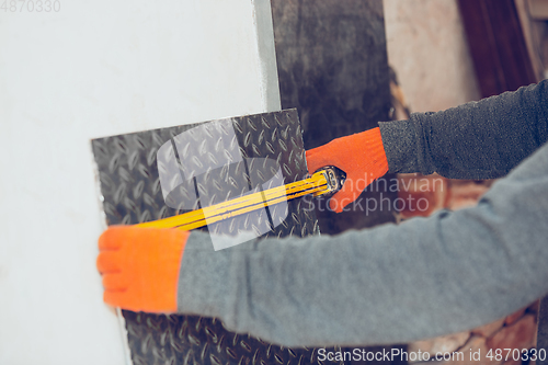 Image of Close up of hands of repairman, professional builder working outdoors, measuring