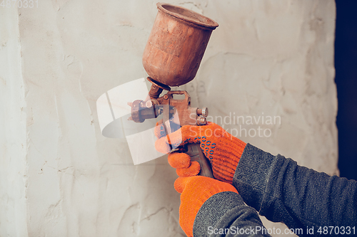 Image of Close up of hands of repairman, professional builder working indoors, coloring the wall