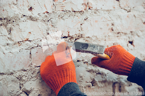 Image of Close up of hands of repairman, professional builder working indoors, hammer a dowel with a screw into the wall