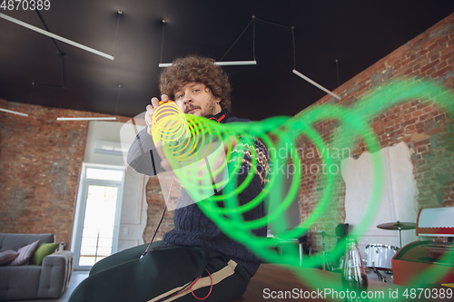 Image of Portrait of millenial boy using retro toys, meeting things from the past and having fun, nostalgic, using rainbow spring toy