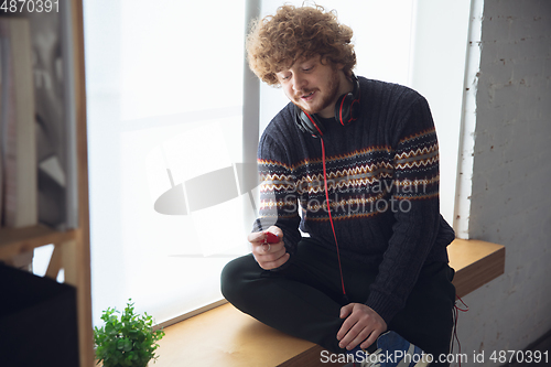 Image of Portrait of millenial boy using retro toys, meeting things from the past and having fun, nostalgic, playing tamagotchi, virtual pet