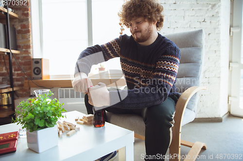 Image of Portrait of millenial boy using retro toys, meeting things from the past and having fun, nostalgic, playing wooden constructor