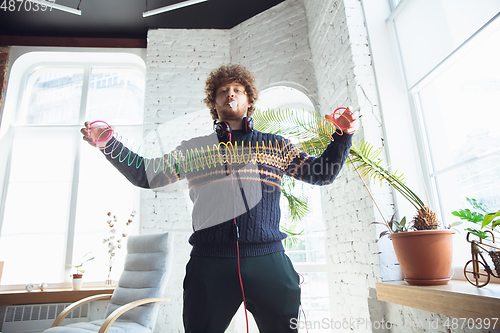 Image of Portrait of millenial boy using retro toys, meeting things from the past and having fun, nostalgic, using rainbow spring toy