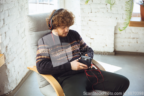 Image of Portrait of millenial boy using retro toys, meeting things from the past and having fun, nostalgic, listen to music with cassette player