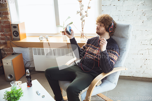 Image of Portrait of millenial boy using retro toys, meeting things from the past and having fun, nostalgic, listen to music with cassette player