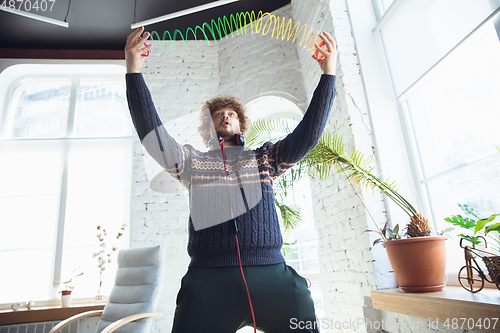 Image of Portrait of millenial boy using retro toys, meeting things from the past and having fun, nostalgic, using rainbow spring toy