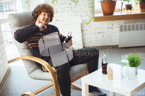 Image of Portrait of millenial boy using retro toys, meeting things from the past and having fun, nostalgic, listen to music with cassette player