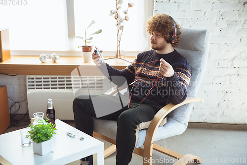 Image of Portrait of millenial boy using retro toys, meeting things from the past and having fun, nostalgic, listen to music with cassette player