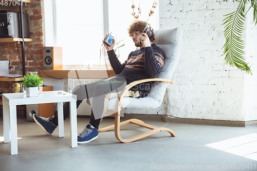 Image of Portrait of millenial boy using retro toys, meeting things from the past and having fun, nostalgic, listen to music with cassette player