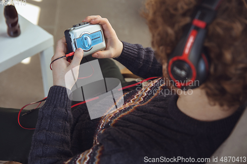 Image of Portrait of millenial boy using retro toys, meeting things from the past and having fun, nostalgic, listen to music with cassette player