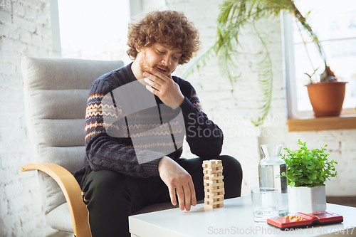 Image of Portrait of millenial boy using retro toys, meeting things from the past and having fun, nostalgic, playing wooden constructor