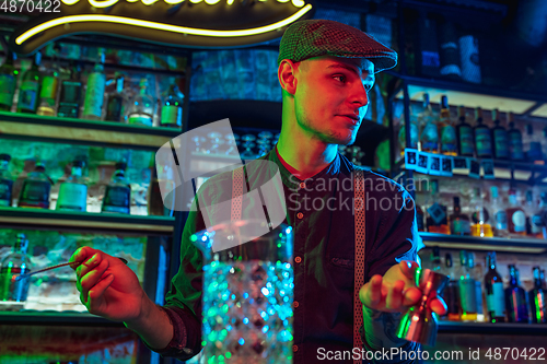 Image of Barman proposing alcoholic cocktails, shots, beverages to guest in multicolored neon light