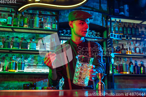 Image of Barman proposing alcoholic cocktails, shots, beverages to guest in multicolored neon light