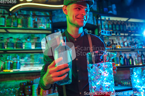 Image of Barman proposing alcoholic cocktails, shots, beverages to guest in multicolored neon light