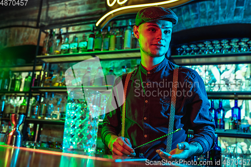 Image of Barman proposing alcoholic cocktails, shots, beverages to guest in multicolored neon light