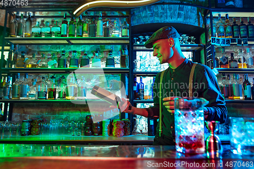 Image of Barman preparing alcoholic cocktail in multicolored neon light