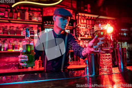 Image of Barman proposing alcoholic cocktails, shots, beverages to guest in multicolored neon light