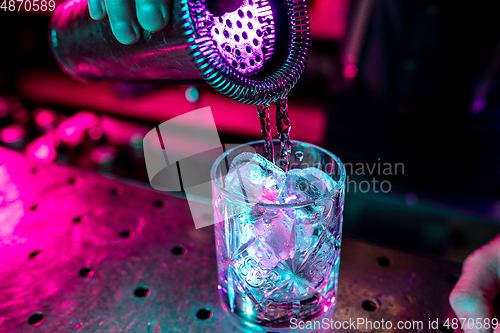 Image of Close up of alcoholic cocktail, beverage, drink, glass full of ice in multicolored neon light