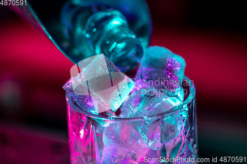 Image of Close up of alcoholic cocktail, beverage, drink, glass full of ice in multicolored neon light