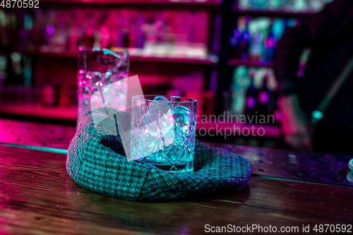 Image of Close up of alcoholic cocktail, beverage, drink, glass full of ice in multicolored neon light