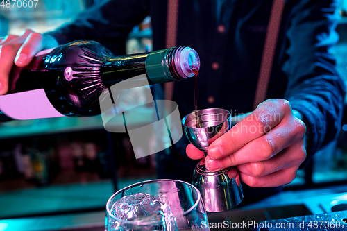 Image of Close up of barman preparing of alcoholic cocktail with shot in multicolored neon light