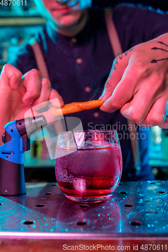 Image of Close up of barman decorating, preparing of alcoholic cold cocktail in multicolored neon light