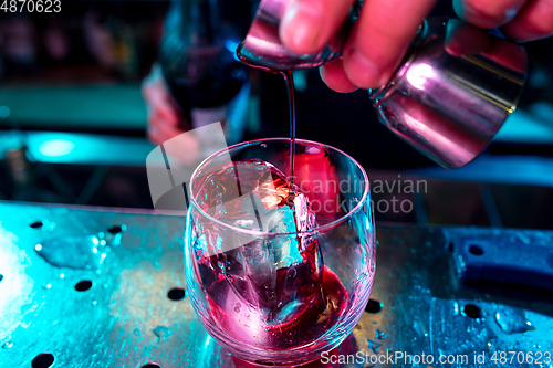 Image of Close up of barman preparing of alcoholic cocktail with shot in multicolored neon light