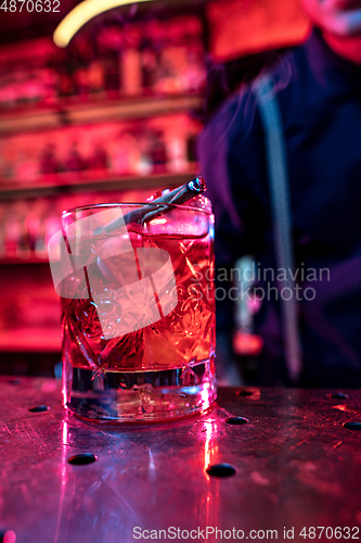 Image of Close up of alcoholic cocktail, beverage, drink, glass full of ice in multicolored neon light